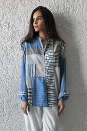 Woman wearing a patchwork shirt against a textured wall