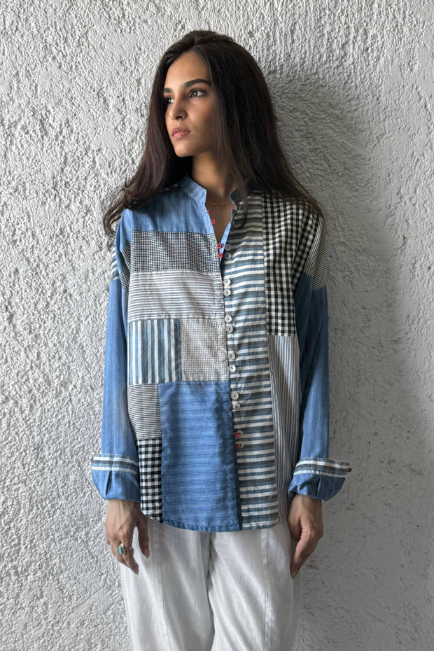 Woman wearing a patchwork shirt against a textured wall
